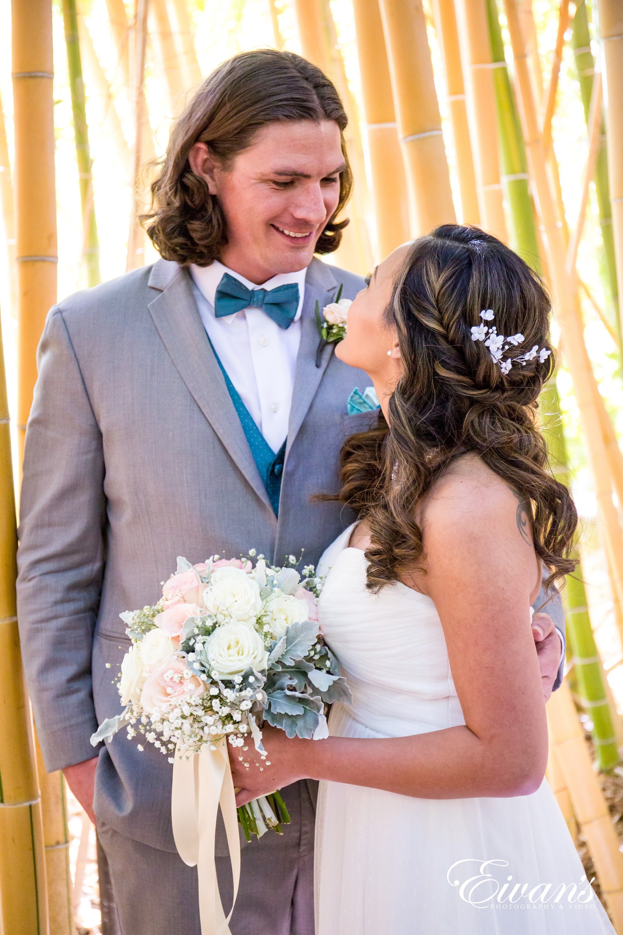 man in blue suit and woman in white wedding dress holding bouquet of flowers