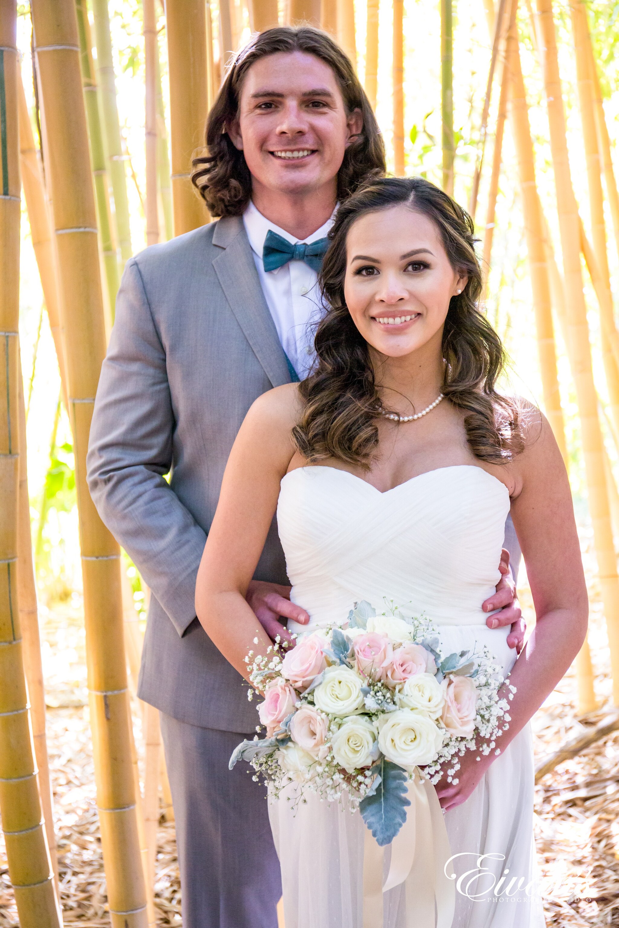 man in gray suit jacket hugging woman in white wedding dress